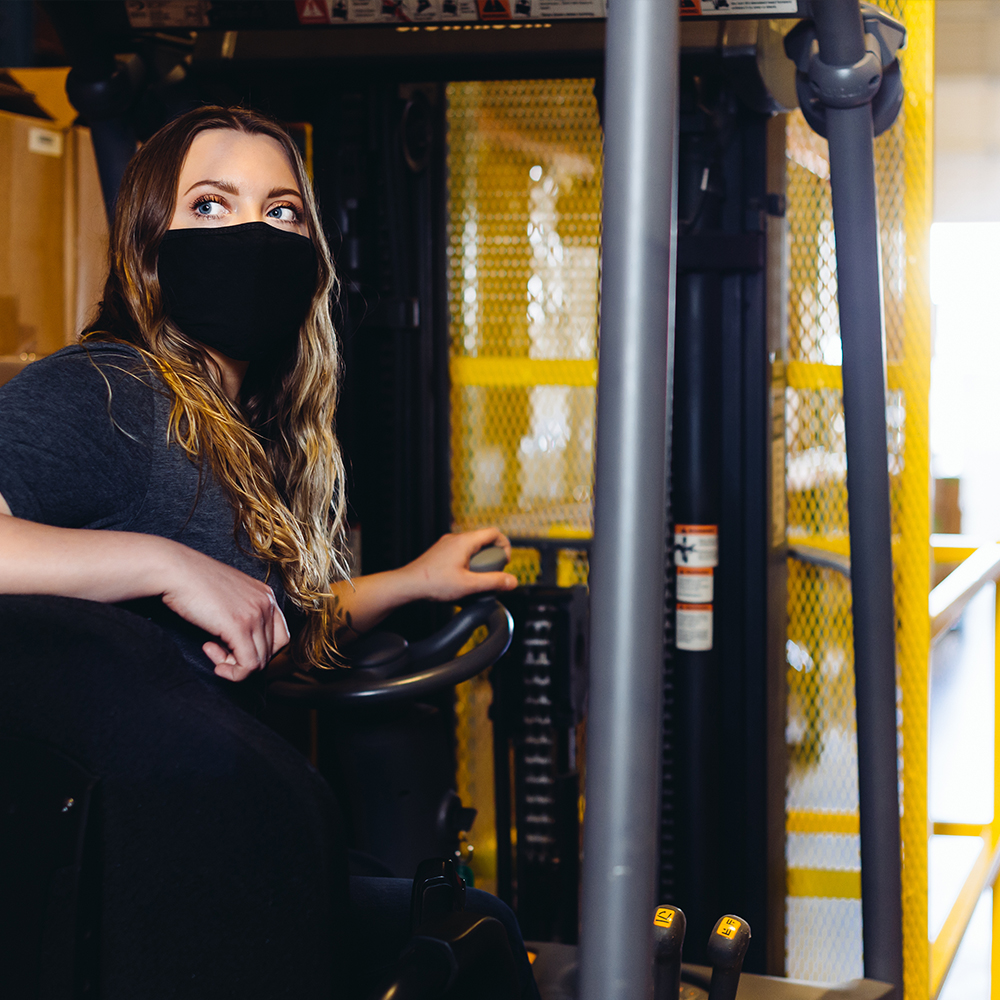 A forklift being driven by a masked employee